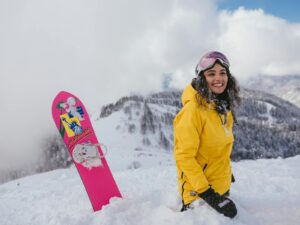une femme heureuse avec un snowboard à la montagne